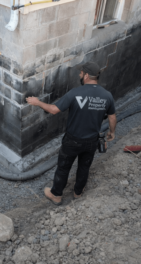 Valley property management employee assessing the damage caused by water on a foundation.